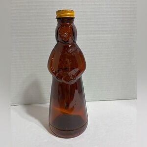 Vintage Mrs. Butterworth's amber glass syrup bottle with a metal cap.